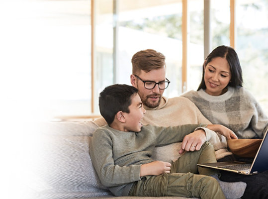 Une mère et un père sur le canapé avec leur enfant utilisant un ordinateur portable Windows 10