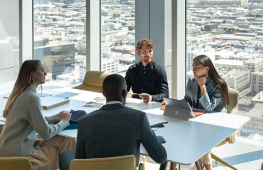 Vier Personen sitzen in einem Büro