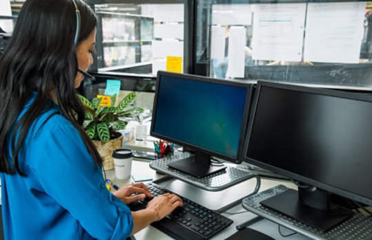 Frau sitzt am Bürotisch und blickt auf einen Monitor