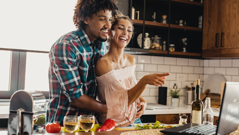 Photo credit: blackCAT/E+/Getty Images. Smiling man and woman look at recipe on Windows 11 laptop while cooking together in kitchen