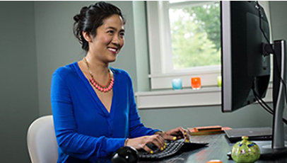 Woman sitting at desk smiling at monitor while typing on her keyboard