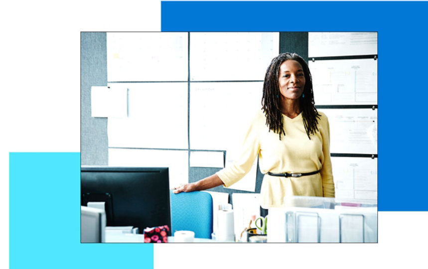 A smiling woman standing behind her desk 