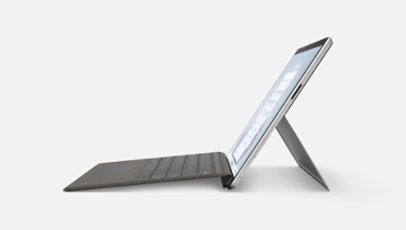 Surface Pro 9 is seen from the side with a type cover attached and the kickstand extended.