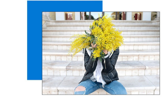 A person sitting and holding a bouquet of flowers in front of their face. 