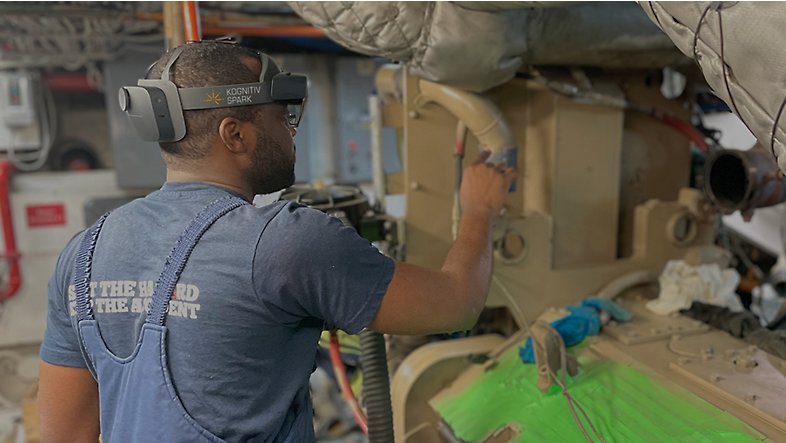 Човек, носещ HoloLens 2 и работещ с машина.