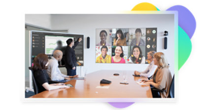 Five people in a meeting room participating in a Teams video call being displayed on a wall while a presentation is being displayed on a large screen.