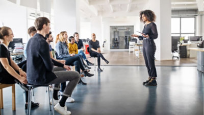 Una persona habla delante de un equipo en una oficina de espacio abierto.