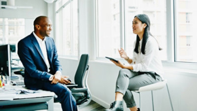 Dos personas conversan en un escritorio de una oficina.