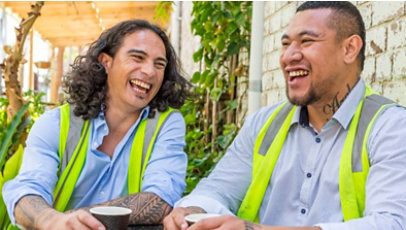 Two men in safety vests, sitting and laughing together