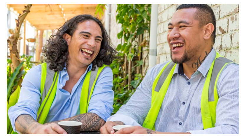 Two men in safety vests, sitting and laughing together