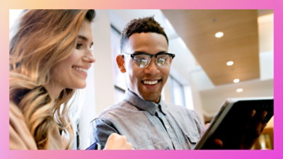 Dve osobe se nasmeju i gledaju u tablet.