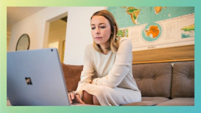 Osoba sedi na kauču i koristi laptop.