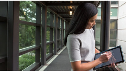 Woman working on her tablet outside of a building.