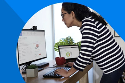 A person standing over their desk typing on a keyboard.