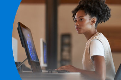 A person standing over their desk typing on a keyboard.