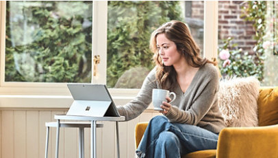 Woman on tablet while holding a cup of tea