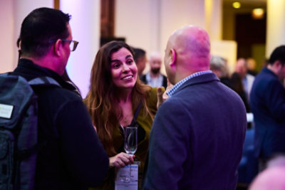  People networking at a reception event in a softly lit venue.