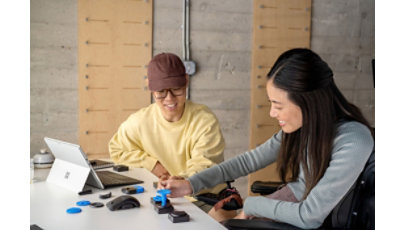 Two people at a desk creating an adaptive device.