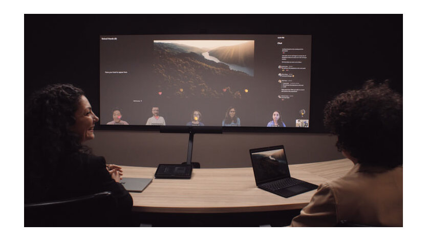 Two employees in a physical meeting room are shown meeting with six employees attending virtually using the Front Row display option available in Microsoft Teams Rooms.