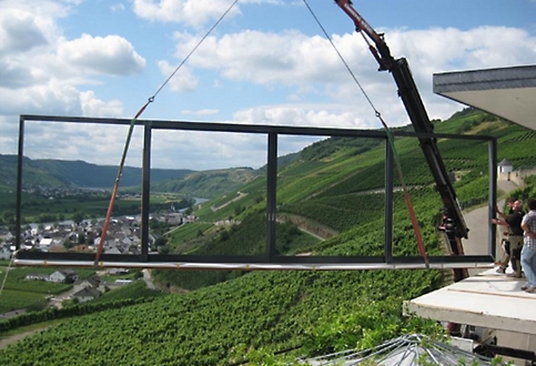 A large window frame being lifted up a mountain.