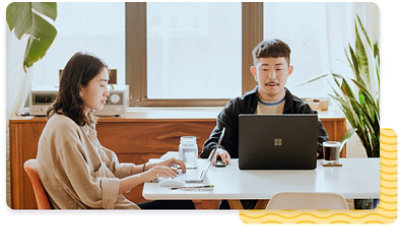 Two people using laptops on large table
