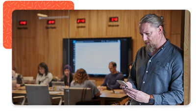 Person outside of conference room looking at mobile phone