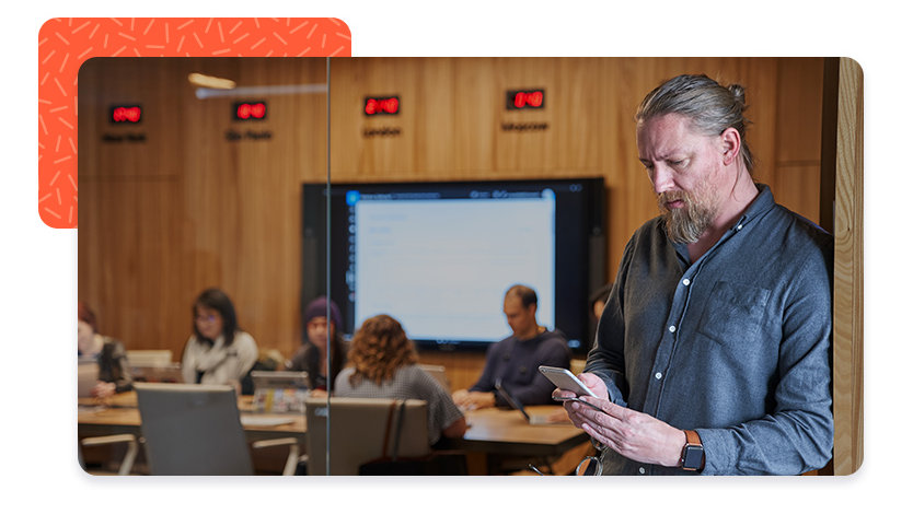 Person outside of conference room looking at mobile phone