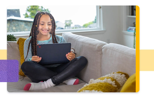 Young person sitting comfortably and smiling on a sofa with a tablet in hand