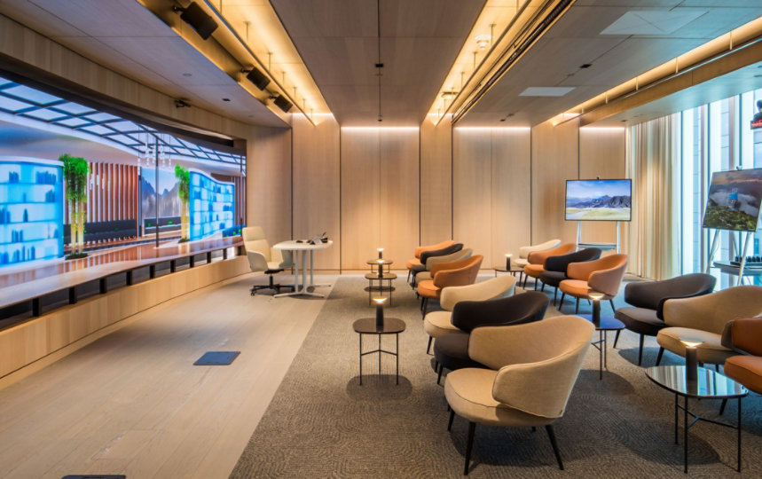 London envisioning theater - a side shot of a room with light wood walls, a large LED screen on one wall and empty casual seating.
