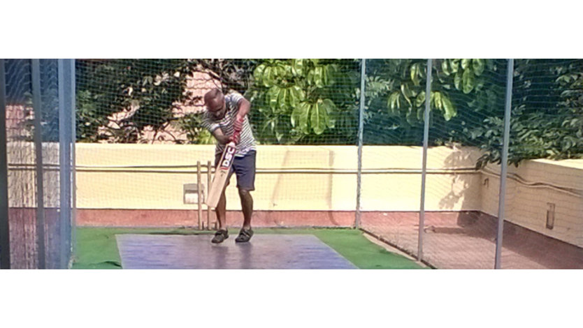 Srikantan Sankaran playing cricket in a netted training area in the sun