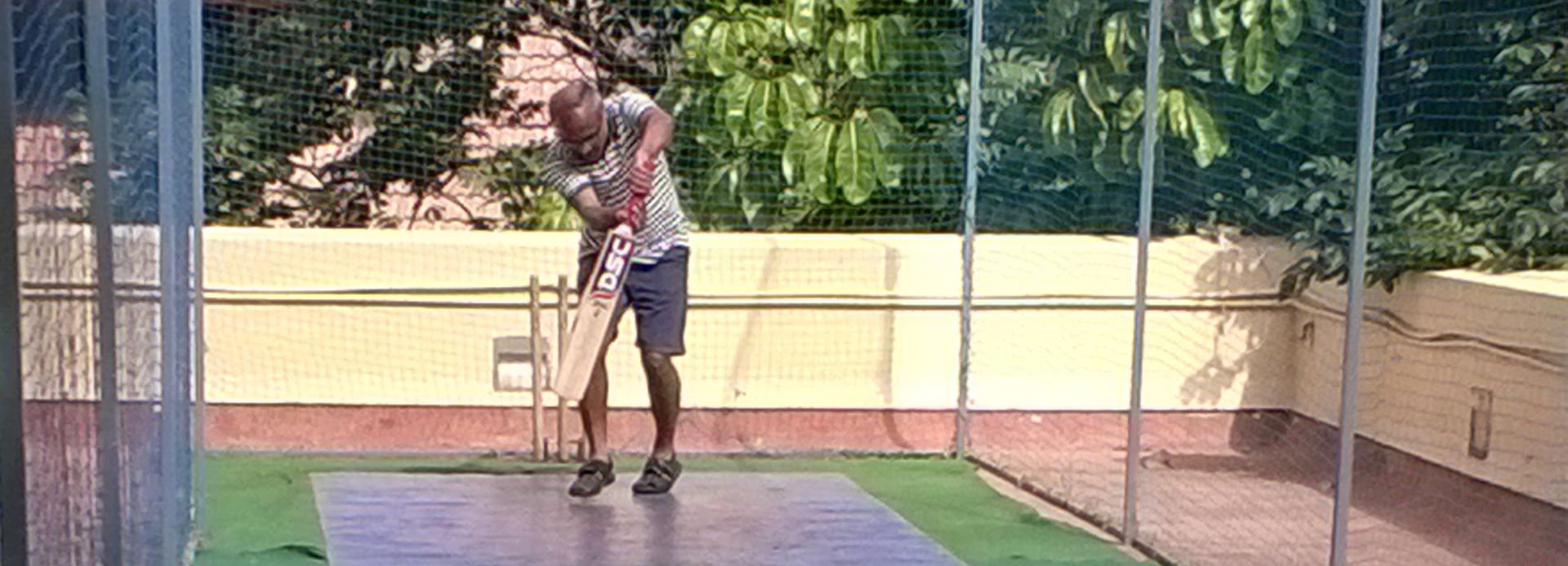 Srikantan Sankaran playing cricket in a netted training area in the sun