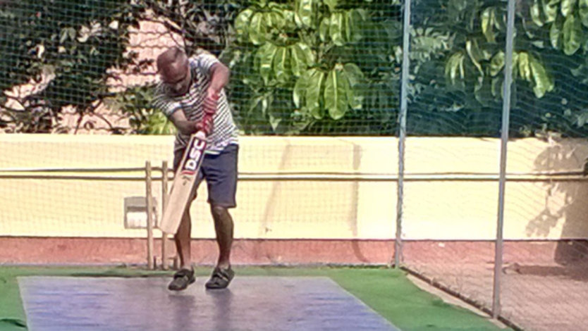 Srikantan Sankaran playing cricket in a netted training area in the sun