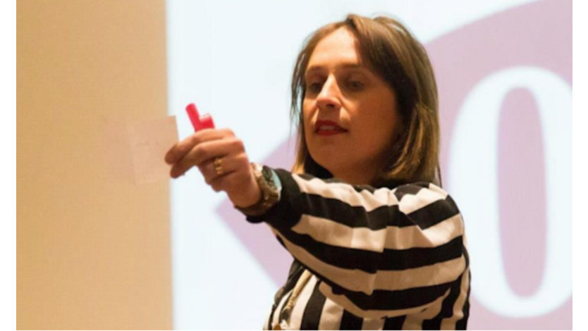 Severine Guilliet in a black and white striped with an outstretched arm holding a small piece of paper