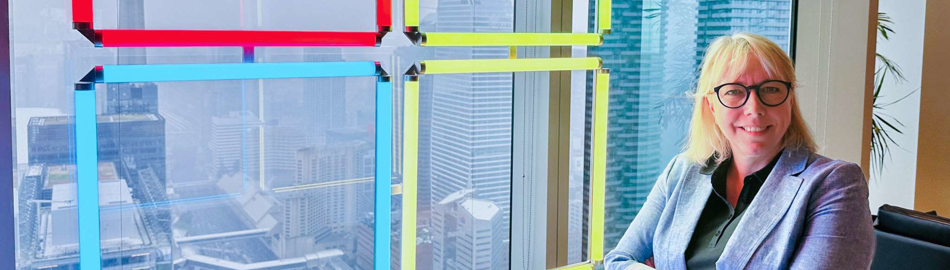 Christine Trudeau of MTC Canada stands beside a window in the Toronto MTC. A Microsoft logo is illuminated through the glass.