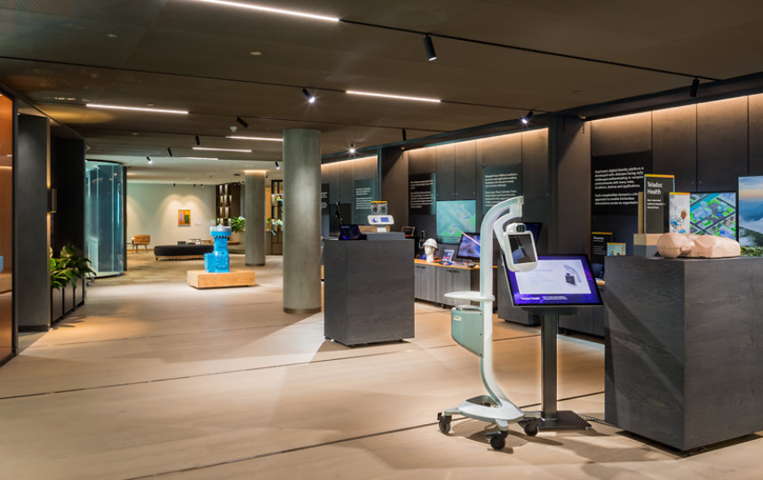 London experience zone - wide shot of an area with dark wood walls, light wood floor, containing demonstration props such as a bright blue industrial pump and a telemedicine machine on casters.