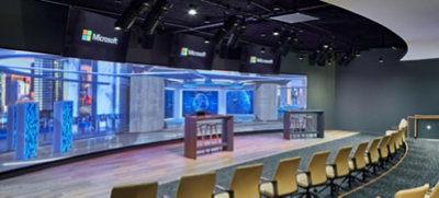 Two rows of chairs face a wide LED wall with a rendered fictitious image of a cyber security operations center
