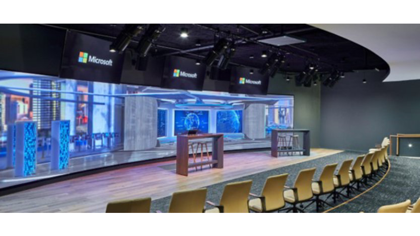 Two rows of chairs face a wide LED wall with a rendered fictitious image of a cyber security operations center