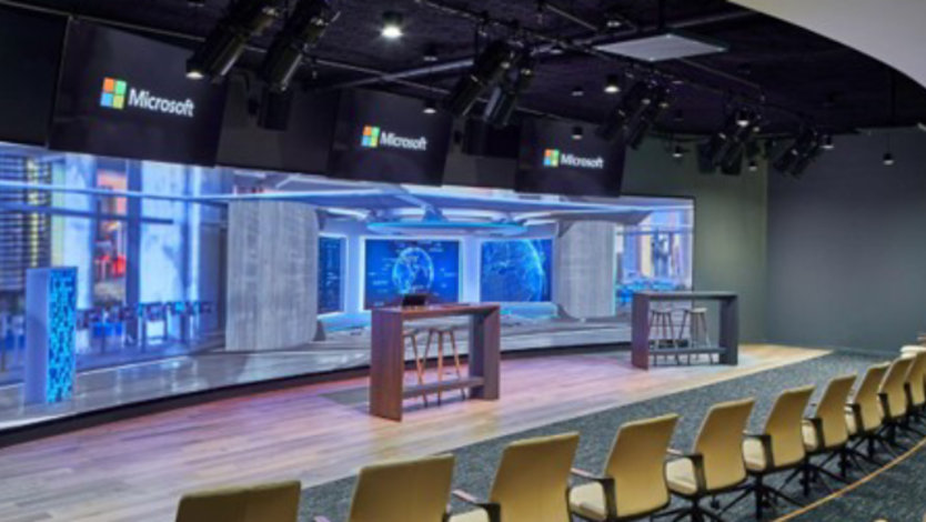 Two rows of chairs face a wide LED wall with a rendered fictitious image of a cyber security operations center