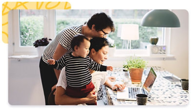 Couple gathered at a laptop on the kitchen table with a toddler