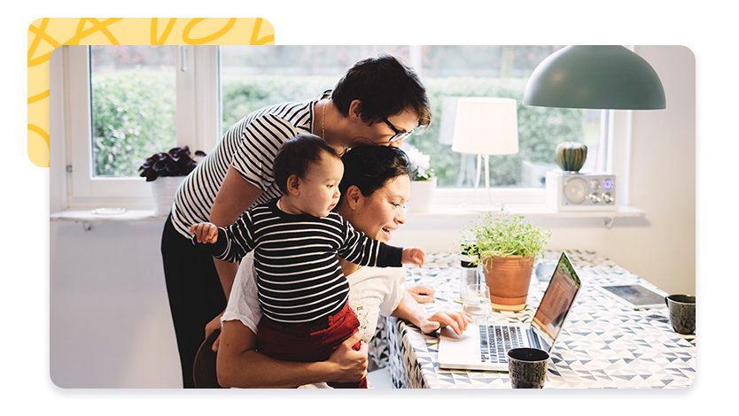 Couple gathered at a laptop on the kitchen table with a toddler