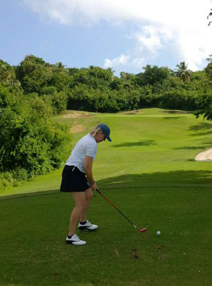 Christine Trudeau at the tee of a lush green golf course about to drive the ball on summer day with slight cloud