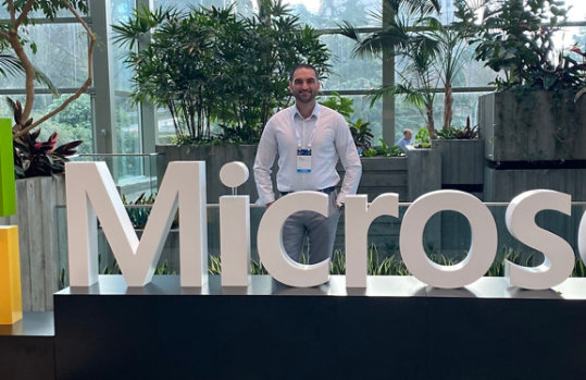Sam Istephan stood behind a large Microsoft sign at a convention