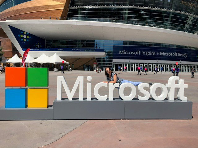Severine Guilliet laying atop a huge 3D Microsoft sign outside a convention 