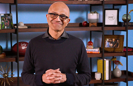 Satya Nadella standing in front of a shelving unit.