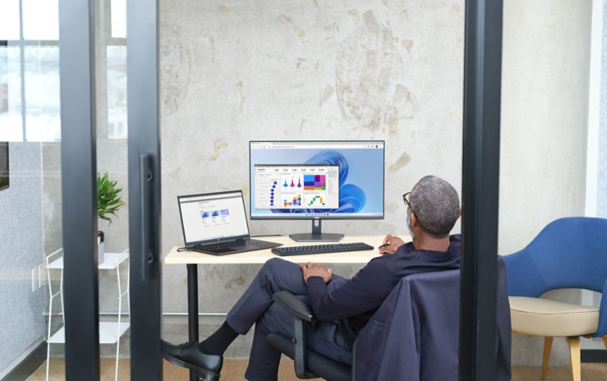 Man sitting in an office viewing Power BI UI within Windows 365, shown on Windows 11.