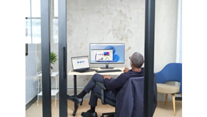 Man sitting in an office viewing Power BI UI within Windows 365, shown on Windows 11.