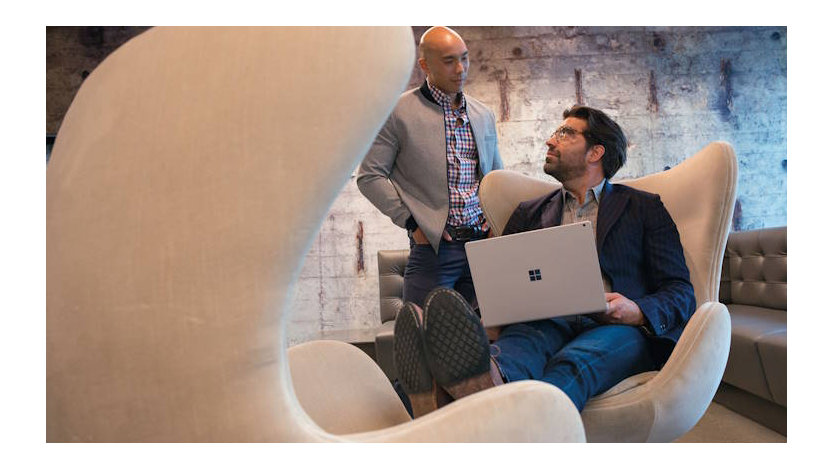 Businessmen in office building collaborating on laptop.