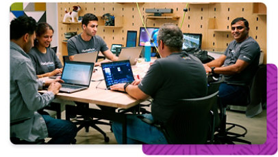 A group of Microsoft employees wearing Hackathon apparel, together working on laptops