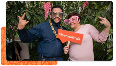 Two Microsoft employees posing for a picture, holding a #MicrosoftLife sign