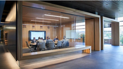 Outside of a conference room or board room meeting including people sitting around table in a room with international time clocks.